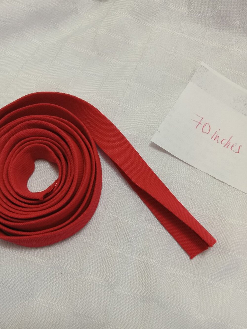 Folded red fabric bias tape, commonly used in sewing to edge or finish necklines